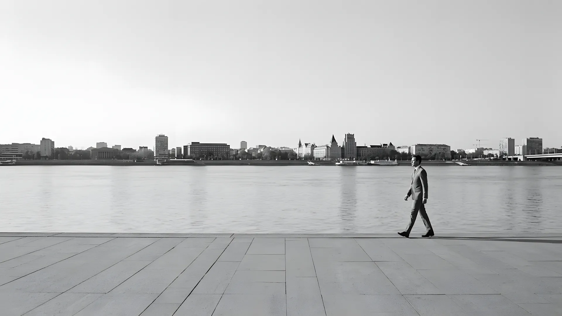 A man in a suit walking along a waterfront